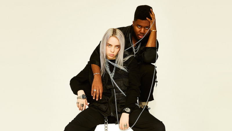 billie eilish with blonde hair, rings and necklances wearing a black and staying on a white cube , and khalid staying behind her wearing black, with his left hand over his head and right hand over billie, everything on a cream background, lovely new song